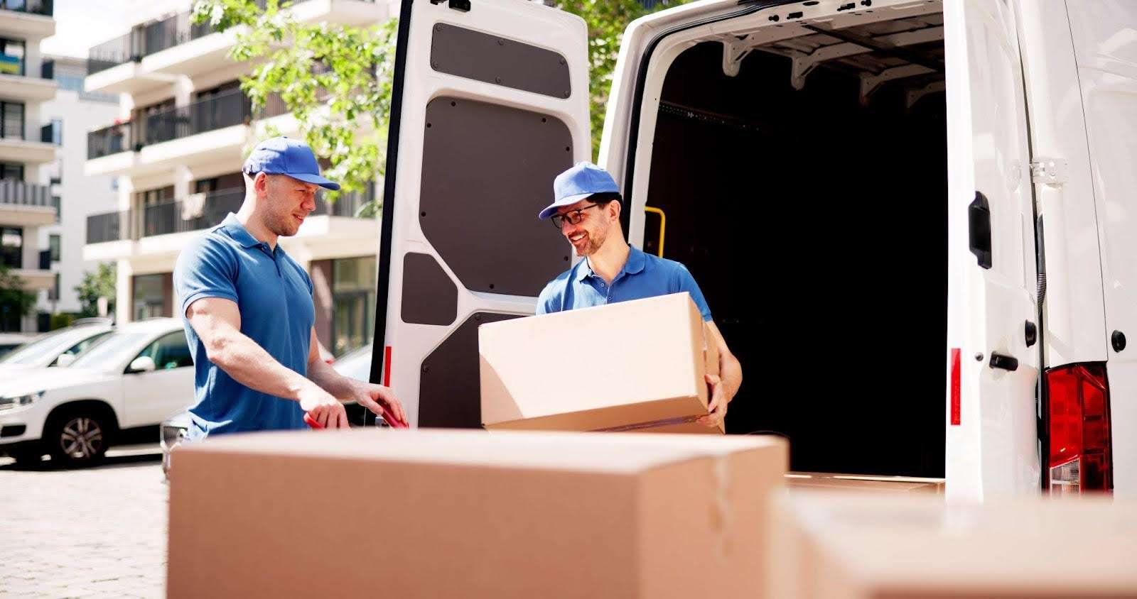 Mover unloading van and carrying boxes with a smile.