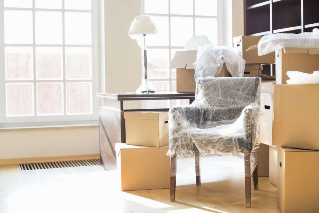 A chair and other furniture wrapped in plastic and surrounded by boxes inside a customer’s home