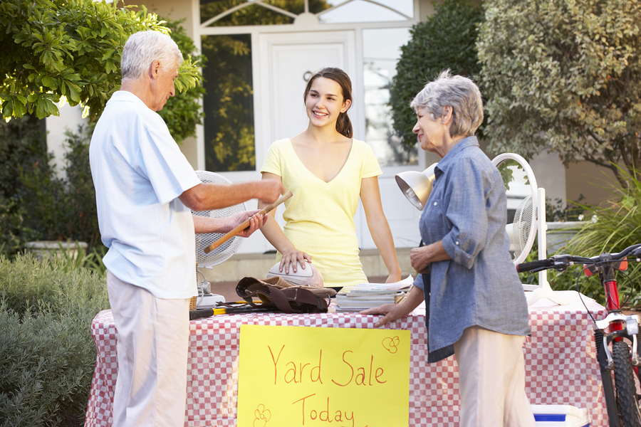 Moving sale outdoors with young girl and older couple shopping